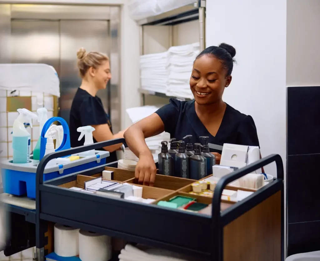 INICIO Chica limpiando con un carro de limpieza, con toallas y otra chica al fondo