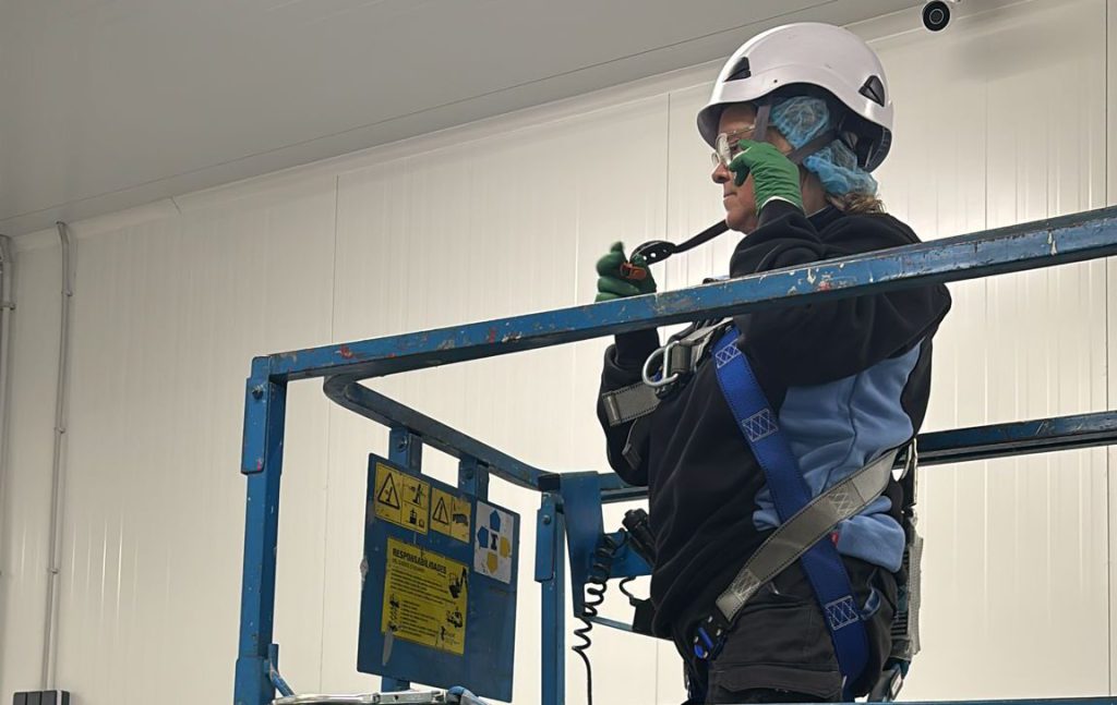 Operaria de Pulim usando una plataforma elevadora en interior
